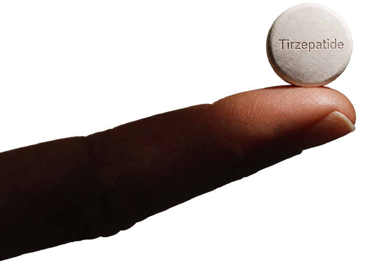 A compounded tirzepatide oral tablet balanced on a fingertip, showing its true size